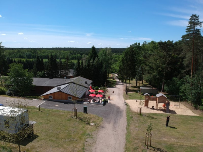 Aerial view of the Safari tent at Camping Sonnenberg in Germany, surrounded by forest, playground and blue sky.