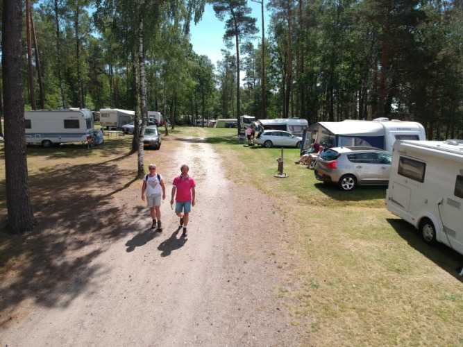 Two people walk on a dirt road surrounded by caravans and tents at Camping Sonnenberg in Germany.
