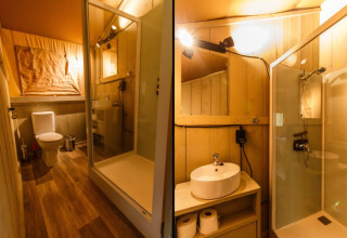 Intérieur salle de bain d’une tente safari avec douche, toilettes et lavabo sous un éclairage chaleureux.