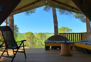 Vue depuis la terrasse d’une tente safari à Casa & Glamping Sorriso, Italie, avec bancs et collines vertes.