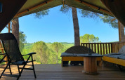 Vue depuis la terrasse d’une tente safari à Casa & Glamping Sorriso, Italie, avec bancs et collines vertes.