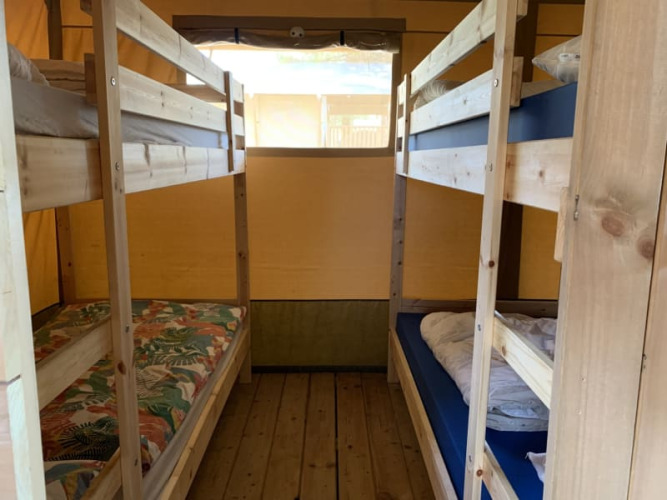 Intérieur d'une tente safari avec lits superposés en bois et plancher à Casa & Glamping Sorriso, Italie.