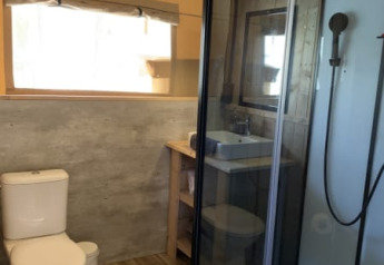 Salle de bain moderne dans une tente safari à Casa & Glamping Sorriso, Italie, avec douche et toilettes.