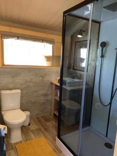 Salle de bain moderne dans une tente safari à Casa & Glamping Sorriso, Italie, avec douche et toilettes.