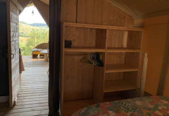 Interno tenda safari a Casa & Glamping Sorriso con scaffali in legno e terrazza con vista natura.