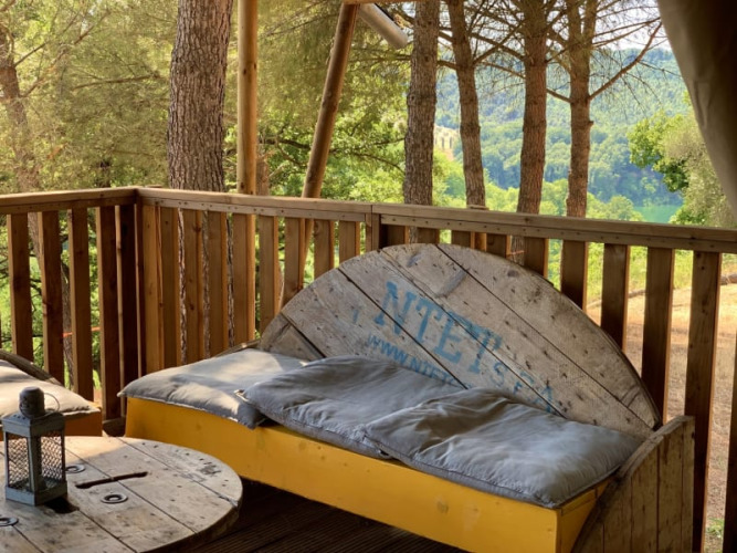 Terrasse en bois avec banc et vue sur la forêt au Safari tent + sanitair, Casa & Glamping Sorriso, Italie.