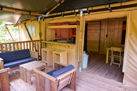 Vue de la terrasse et de l'intérieur de la Safari tent + sanitary au Camping Pittoresque en France.