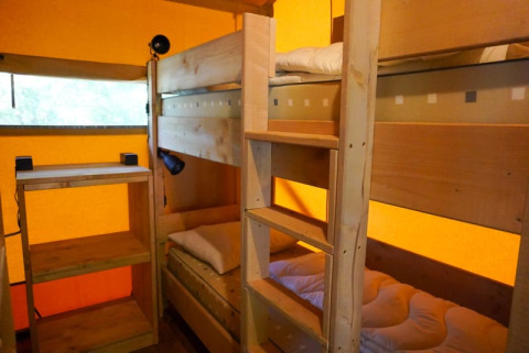 Interieur van de safaritent met stapelbedden en rekjes op Camping Pittoresque in Frankrijk.