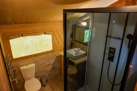 Badeværelse i safari-telt på Camping Pittoresque i Frankrig med bruser, toilet og håndvask.