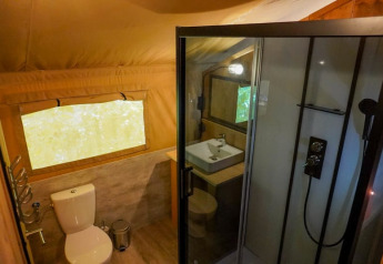 Baño en tienda safari en Camping Pittoresque, Francia, con ducha, inodoro y lavabo modernos.