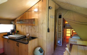 Interieur van een safaritent met kitchenette en stapelbed op Camping Pittoresque in Frankrijk.