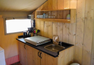 Keukenhoek in safaritent bij Camping Pittoresque, Frankrijk, met gootsteen, rek en keukengerei.