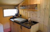 Küchenbereich im Safarizelt bei Camping Pittoresque, mit Spüle, Regal und Kochzubehör, Frankreich.