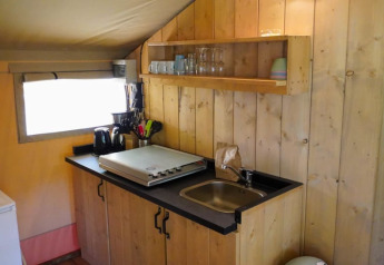 Angolo cucina in tenda safari al Camping Pittoresque in Francia, con lavello, ripiano e utensili visibili.