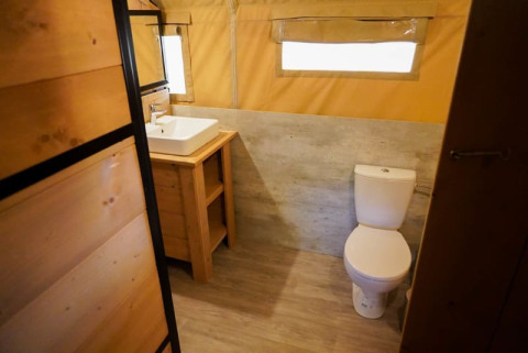 Badkamer in een safaritent met toilet en lavabo bij Camping Pittoresque in Frankrijk.