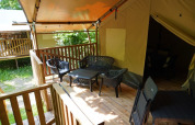 Tienda safari con baño privado en Camping Pittoresque, Francia, con terraza y muebles de exterior.