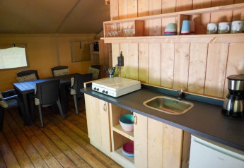 Cocina y comedor de tienda safari con baño privado en Camping Pittoresque, Francia, bien equipada.