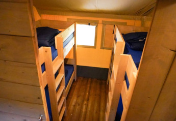 Intérieur d'une tente safari avec lits superposés et sol en bois au Camping Pittoresque en France.