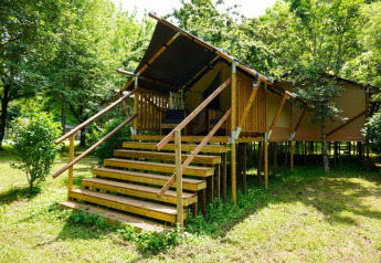 Foto de una tienda safari llamada Duo Lodge, elevada sobre pilotes de madera entre árboles y vegetación verde.