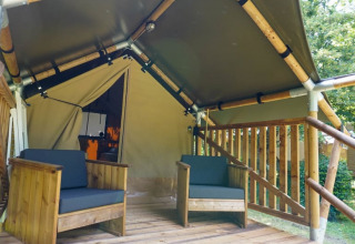 Terraza de madera con dos sillas frente a una tienda safari llamada Duo Lodge en Camping Pittoresque, Francia.