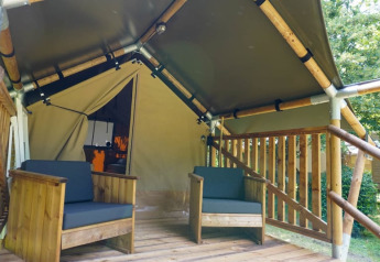 Terraza de madera con dos sillas frente a una tienda safari llamada Duo Lodge en Camping Pittoresque, Francia.