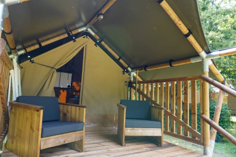 Wooden deck with two chairs outside a safari tent called Duo Lodge at Camping Pittoresque in France.
