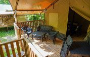 Zona de estar al aire libre en la terraza de una tienda safari con baño en Camping Pittoresque, Francia.