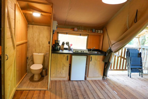 Vista interna di una tenda safari con cucina, bagno e terrazza al Camping Pittoresque in Francia.