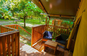 Vista desde la terraza de una tienda safari en Camping Pittoresque en Francia, rodeada de árboles verdes.