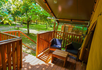 Vista desde la terraza de una tienda safari en Camping Pittoresque en Francia, rodeada de árboles verdes.