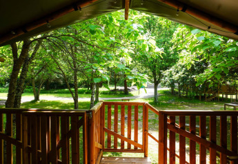 Vista desde la terraza de una tienda safari en Camping Pittoresque, Francia, rodeada de árboles y naturaleza.