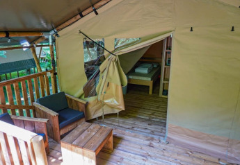 Vista interna ed esterna di una tenda safari al Camping Pittoresque in Francia con mobili in legno.