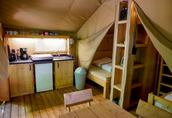 Interieur van een safaritent op Camping Pittoresque in Frankrijk met keukenblok en slaapgedeelte.