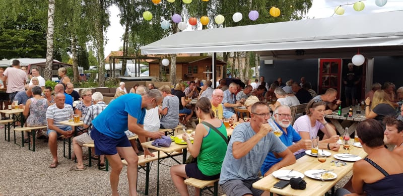 People dining and socializing under colorful lanterns at the safari tent area in Camping Elbeling, Germany.
