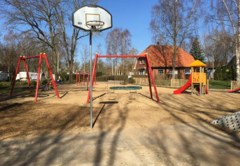Parco giochi con altalene, scivolo e canestro da basket al Camping Elbeling in una giornata soleggiata in Germania.
