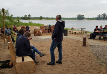 Persone che si rilassano al Safari tent vicino al fiume, sedute su panche di legno in mezzo alla natura.