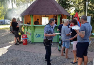 Persone si riuniscono vicino a una griglia in un campeggio con tende presso Camping Elbeling, Germania.