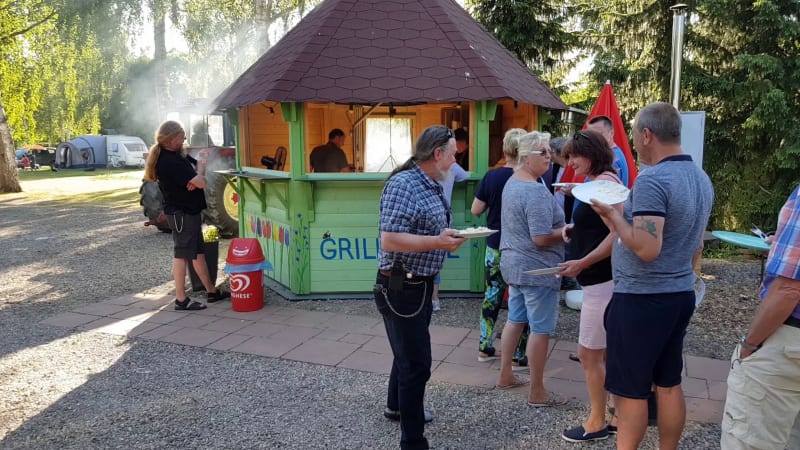 Mensen verzamelen zich bij een grillhut op een camping met tenten bij Camping Elbeling, Duitsland.