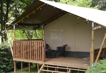 Safari-telt ved Camping L’Etruyère i Frankrig, hævet træterrasse omgivet af grønne træer.