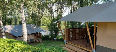 Safari-Zelte auf dem Campingplatz L’Etruyère in Frankreich, umgeben von Bäumen und See in der Nähe.