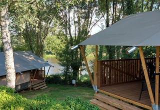 Safari telte på Camping L’Etruyère i Frankrig, omgivet af træer og tæt på en sø, afslappende natur.
