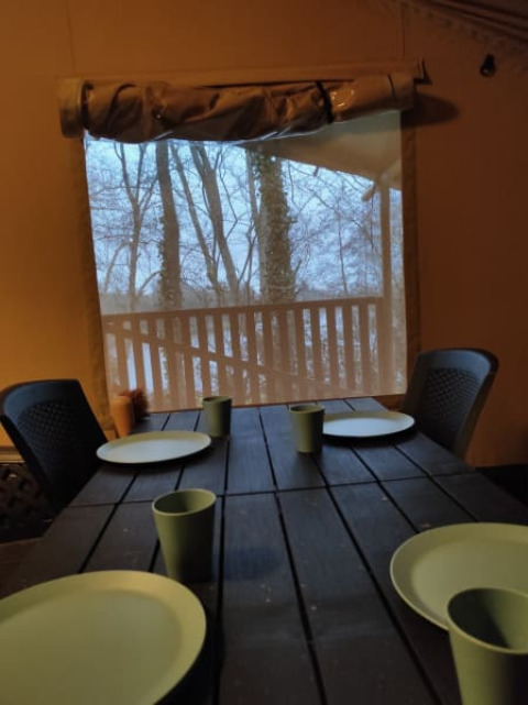 Bord dækket med grønne tallerkener og krus i et safaritelte på Camping L’Etruyère i Frankrig.