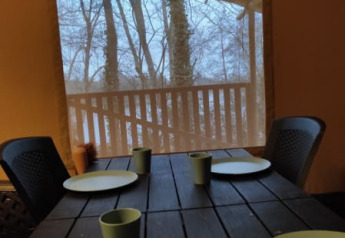 Tavolo apparecchiato con piatti e bicchieri verdi in una tenda safari al Camping L’Etruyère in Francia.