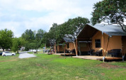 Safari-Zelte auf dem Campingplatz Prima in Tschechien mit Terrasse, viel Grünfläche und Bäumen.