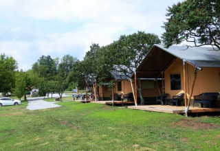 Safari tents at Camping Prima in Czech Republic, featuring wooden decks, green grass, and shady trees.