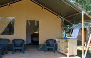Safaritent aan Camping Prima in Tsjechië met buitenstoelen en een kleine keukenruimte.