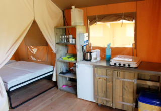 Safaritent op Camping Prima in Tsjechië met bed, kitchenette en houten kasten in gezellige stijl.
