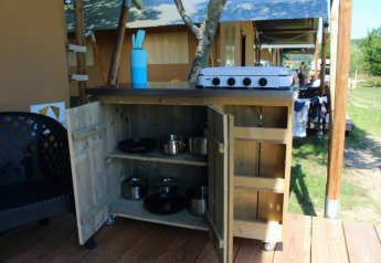 Cucina esterna accanto a tenda safari al Camping Prima in Repubblica Ceca con fornello, pentole e utensili.