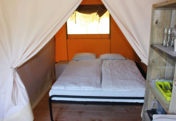 Indvendig udsigt af en safari-telt på Camping Prima i Tjekkiet, med dobbeltseng og træhylder.