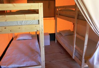 Inde i en safari-telt på Camping Prima i Tjekkiet med køjesenge og en hyggelig atmosfære.